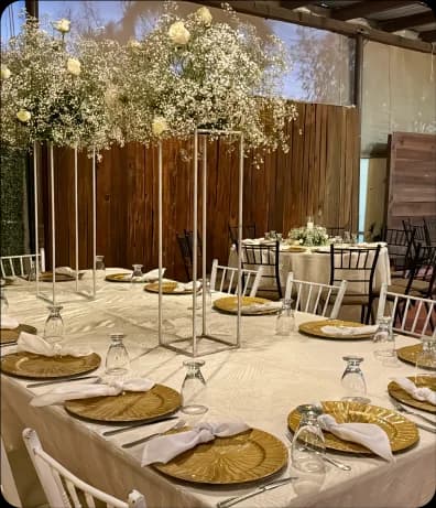 Cristalería en la mesa de un evento, la mesa tiene decoraciones florales en el centro y presenta colores claros