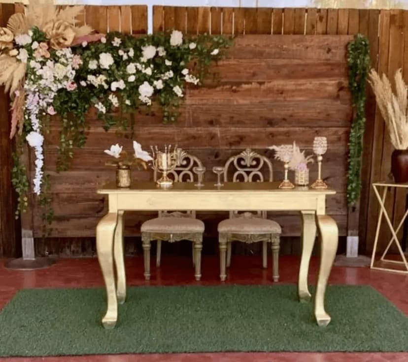 Mesa de honor número 14 con un fondo de madera, decorada con hojas verdes y flores blancas en un estilo minimalista y rústico.