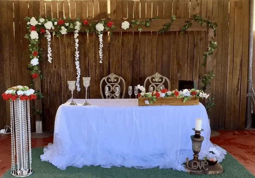Mesa de honor número 4 con una decoración minimalista en blanco, adornada con flores rojas y blancas para un toque elegante.